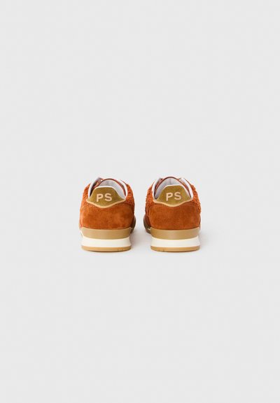 Un paio di sneaker in suede color ruggine con inserti in pelle color beige sul tallone, contrassegnati con "PS", mostrati dal retro su uno sfondo bianco.