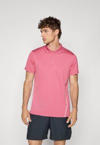 Camisa polo rosa com colarinho clássico, três botões, mangas curtas e um detalhe branco de lado. O tecido parece liso e ajustado.