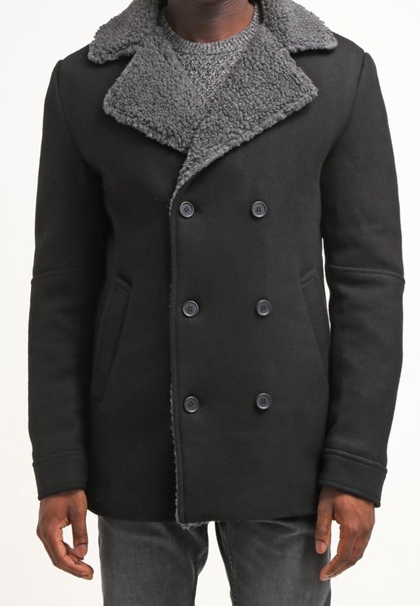 Svart dubbelknäppt rock med en grå shearling-krage, utrustad med sidofickor och knäppningar, tillverkad av ett texturerat tyg.