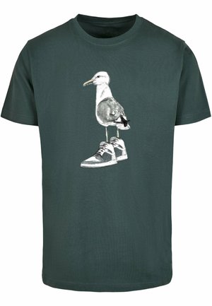 Khaki green t-shirt featuring a graphic of a seagull wearing grey sneakers with white laces. Fabric texture is smooth and plain.