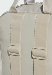 Mochila beige con tejido grueso y texturizado, correas dobles ajustables con hebillas de plástico y un cierre de cremallera en la parte superior.