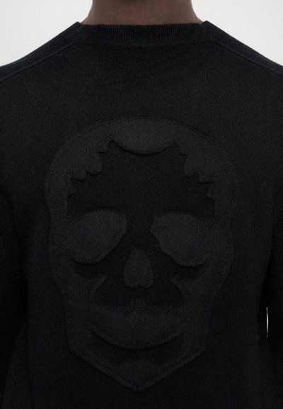 Black sweater featuring a subtle embossed skull design on the back, worn by a person shown from behind.