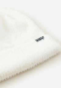 Soft white knit beanie with a folded brim and a small black "Rip Curl" logo tag on the side.