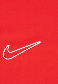 Roter Stoff mit glatter Textur, der auf der rechten Seite ein auffälliges weißes Nike-Swoosh-Logo zeigt. Einfaches, klares Design.