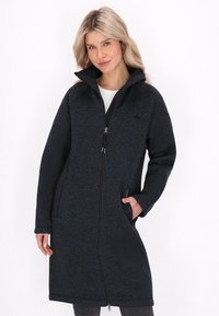 Cappotto lungo in tessuto di un blu scuro, con colletto alto, zip completa, tasche laterali e una silhouette rilassata. Adatto per l'abbigliamento casual.