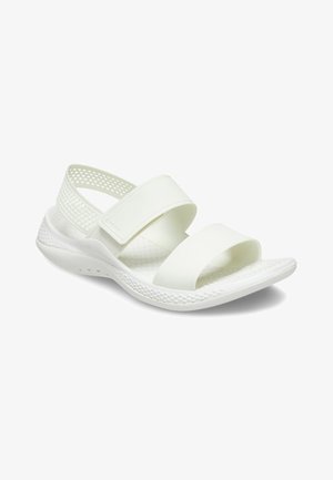 Witte sandalen met brede, platte riemen, mesh details en een gestructureerde zool voor grip. Het ontwerp is lichtgewicht en minimalistisch.