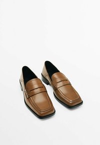 Une paire de mocassins en cuir marron avec des bouts carrés et des semelles noires sur un fond blanc.