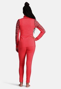 Rotes Sportoutfit bestehend aus einem Oberteil mit hohem Kragen und gemusterten Ärmeln sowie eng anliegenden Hosen. Hergestellt aus weichem, dehnbarem Material.