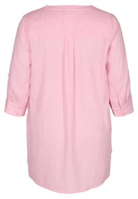 Camicia tunica in lino rosa con maniche a tre quarti, dettaglio di piega sul retro e polsini bottonati. Tessuto morbido e lunghezza maggiore per una facile vestibilità.