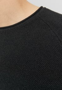 Fekete kötött pulóver, textúrált mintával, kerek nyakkivágással és rövid ujjakkal, részletes varrással a varratok mentén.