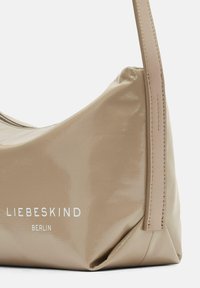 Borsa a tracolla in pelle patinata beige con una forma curvata, dotata di una tracolla piatta, dettagli cuciti e il logo "LIEBESKIND BERLIN" stampato in bianco.
