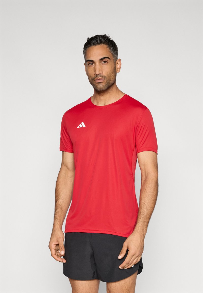 Punane lühikeste varrukatega sportlik särk, valmistatud kerge kangaga, millel on ümar kaelus ja valge kolme triibuga logo vasakul rinnal.