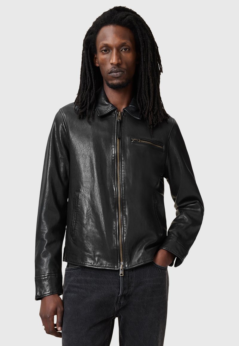 Black leather jacket with a zip front, a small chest pocket, and a classic collar. Features a smooth texture and minimalistic design.