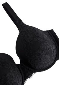 Musta rintaliivi, jossa on pitsikoristelu kupuilla, sileä kangas ja säädettävät olkaimet. Sen muoto on pyöreä ja pitsissä on kukkakuviota.