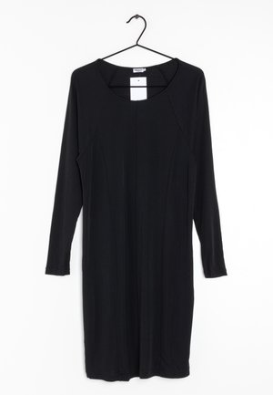 Robe noire à manches longues, longueur genou, avec un col rond, suspendue à un cintre noir sur un fond blanc.