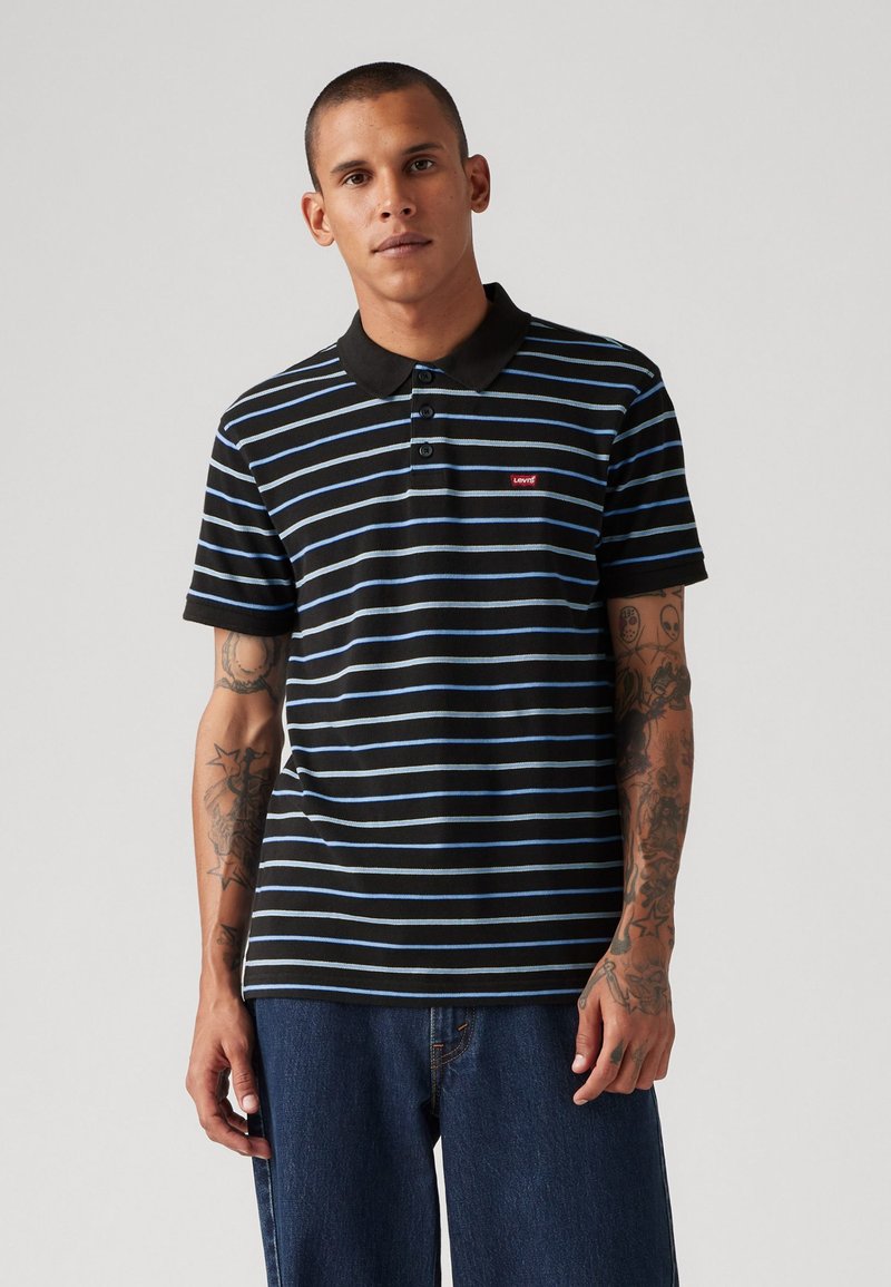 Black and blue striped polo shirt with a black collar, three-button placket, and a small red logo patch on the chest. Soft cotton material.