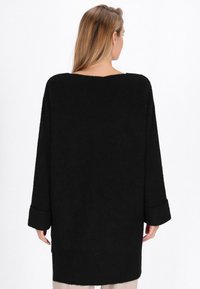 Pulover negru extra-large cu un model tricotat texturat, mâneci largi și un decolteu rotund. Spatele are un design simplu, fără embellismente.