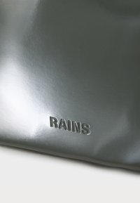 Sivi vodootporni ruksak s sjajnom površinom, s urezanim logotipom "RAINS" u donjem lijevom kutu. Glatka tekstura i elegantan dizajn.