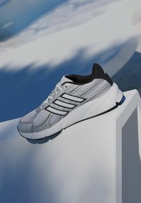 Biela športová obuv s vrchnou časťou z sieťoviny so sivými akcentmi, tromi čiernymi pruhmi, textúrovanou gumovou podrážkou a polstrovaným čiernym golierom.