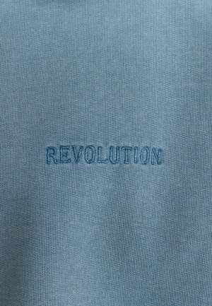 Light blue fabric with a ribbed texture featuring the embroidered word "REVOLUTION" in darker blue.