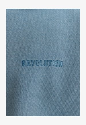 Light blue fabric with a ribbed texture featuring the embroidered word "REVOLUTION" in darker blue.