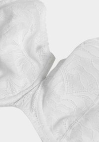 Reggiseno bianco in pizzo con motivi floreali, texture morbida e bordi scallopati, dotato di coppe imbottite e spalline regolabili.