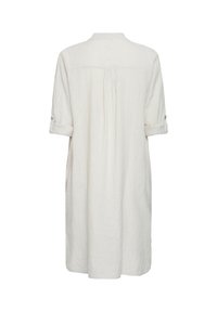 Longue robe blanche en lin avec manches retroussées maintenues par des pattes à boutons, vue de dos.