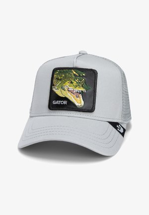 Gorra gris con un panel frontal sólido, que presenta un parche de cocodrilo bordado. Parte trasera de malla, visera curvada y logo de la marca en el lado.