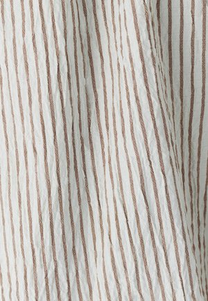 Tessuto rugoso con strisce verticali alternate bianche e marrone chiaro, che mostra una superficie testurizzata e un materiale leggero.