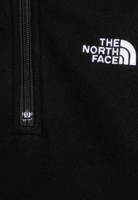 Pullover in fleece nero con zip a metà, caratterizzato da un logo ricamato bianco sul petto e una texture liscia e morbida.