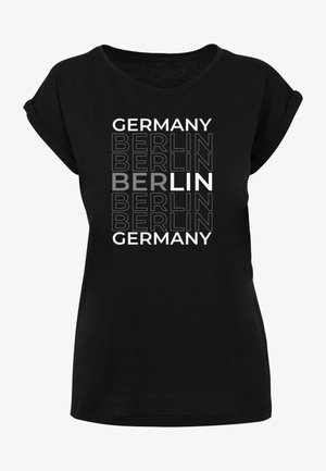 T-shirt noir avec un design graphique comportant le texte répété "ALLEMAGNE" et "BERLIN" dans diverses polices et couleurs, avec "LIN" mis en avant.
