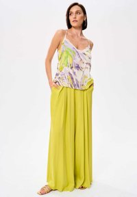 Satin bloemen tanktop met dunne bandjes, gecombineerd met losse, hooggesneden felgele broeken, met diepe zakken en een luchtige textuur.