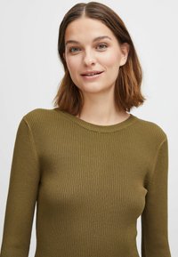 Olivgrön ribbad stickad tröja med rund halsringning och åtskilda långa ärmar, som visar upp textil med struktur och en slät finish.