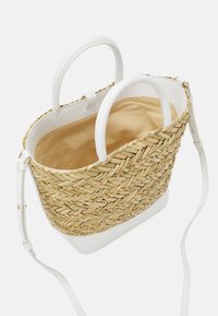 Sac cabas en paille tressée avec poignées et base en cuir blanc, intérieur en tissu beige, et bandoulière amovible en cuir blanc.