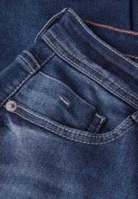Jeans de mezclilla azul oscuro con un bolsillo frontal y costuras visibles. Presentan un botón de metal y un ligero desvanecimiento para mayor textura.