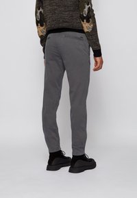 Grå bomulls-chinos med skräddarsydd passform, med bakre fickor med dragkedja och minimala sömdetaljer, kombinerade med svarta snörskor.