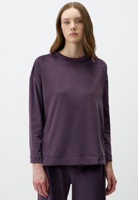 Maglietta a maniche lunghe viola realizzata in tessuto morbido e strutturato, con scollatura rotonda, vestibilità ampia e dettagli di cucitura minimi.