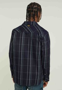 Navy geblokt overhemd met lange mouwen met een wit rasterpatroon, knoopsluiting kraag en contrasterende stiksels, met een ontspannen pasvorm en rugpand.