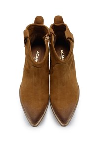 Stivali alla caviglia in suede marrone con punta appuntita, chiusura laterale con zip e dettaglio ad anello sul tallone. Texture liscia e colore uniforme con accenti minimi.