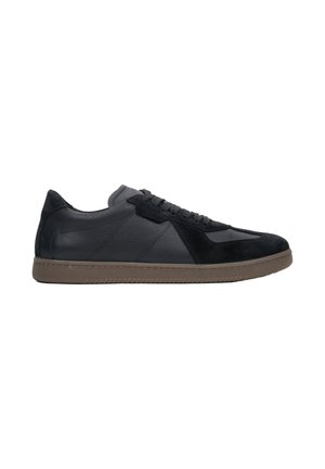 Schwarze Sneaker aus einer Kombination von Leder und Wildleder, mit flachem Design, Schnürverschluss und einer braunen Gummisohle.