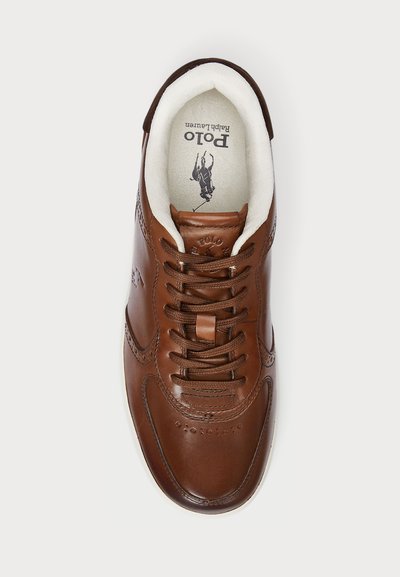 Adidași din piele maro cu vârf rotund, cu șireturi, accente perforate și căptușeală moale albă. Logo-ul "Polo Ralph Lauren" vizibil în interior.