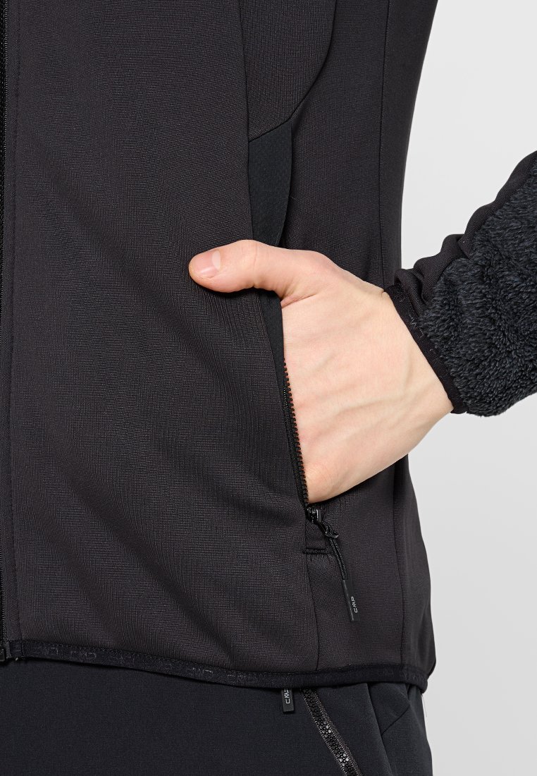 Giacca atletica nera con tessuto testurizzato, colletto alto e tasche con zip. Design slim fit e morbidi accenti in fleece sulle maniche.