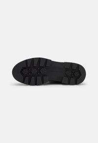 Suela de zapato de goma negra con dibujos profundos y patrones hexagonales, que presenta un perfil plano y bordes reforzados para mayor durabilidad.