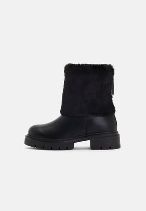 Melni potītes zābaki ar gludu ādas pamatni un teksturētu mākslīgās kažokādas apmali. Masīva, rievota gumijas zole, kas nodrošina labu saķeri.