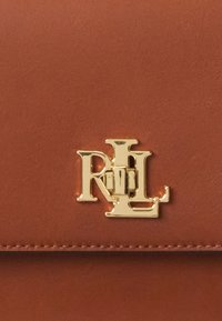 Borsa a tracolla in pelle marrone con logo RL in metallo dorato, texture liscia e design semplice con cuciture visibili lungo i bordi.
