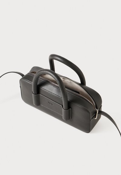 Črna usnjena torba s tremi zgornjimi ročaji, z zadrgo in prednjim logotipom. Ima kontrastne šive in kompaktno pravokotno obliko.