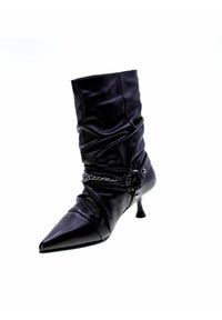 Stivale alla caviglia in pelle nera con design arricciato, punta affusolata, tacco medio e dettaglio in catena alla caviglia. Texture liscia e finitura lucida.