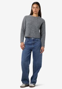 Grayer, kurz geschnittener Pullover mit weicher Textur, kombiniert mit locker sitzenden blauen Jeans. Besonders hervorzuheben ist die entspannte Silhouette und das schlichte Design.