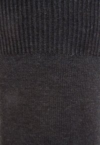 Calcetines negros de canalé con un diseño texturizado. La parte superior presenta un grueso canalé, mientras que la sección inferior es suave y tiene un ligero brillo.