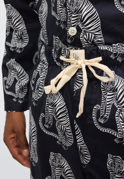 Camicia in tessuto blu navy con stampa di una tigre bianca, dotata di chiusura con bottoni e vita regolabile con coulisse e dettagli beige. Materiale con trama.